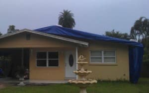 Residential home with a protective blue tarp for storm damage inspections and repairs