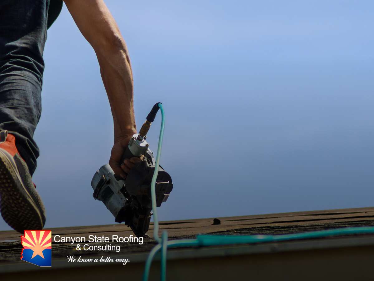 Roofer working on a roof with a nail gun, illustrating Roofing R&R